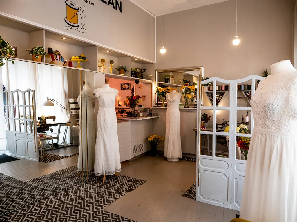 Inside the shop: white wedding dresses on mannequins beside a glass-fronted cabinet
