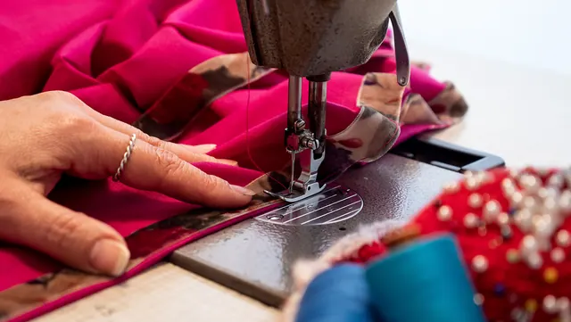 Close-up of a sewing machine stitching bright pink fabric