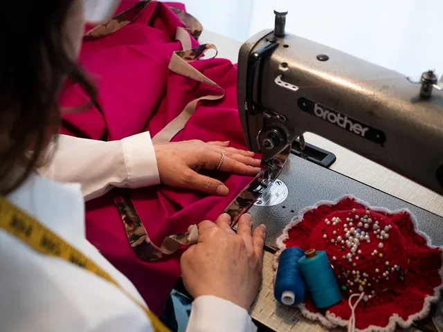 A seamstress guiding pink fabric through an industrial sewing machine