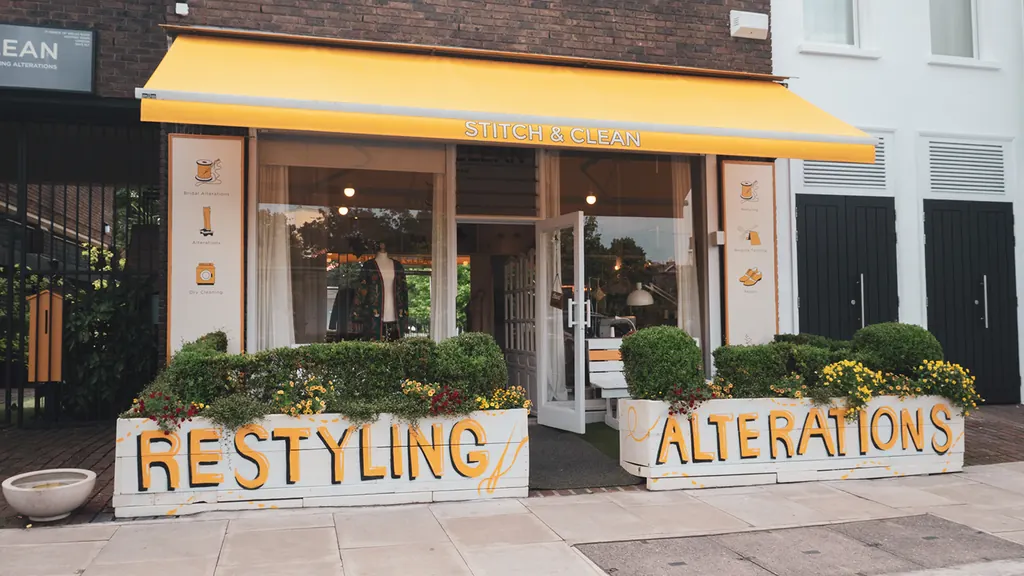 The Stitch House shopfront with its yellow awning and planters painted with the words Restyling and Alterations